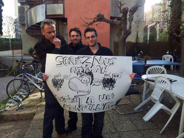 Ancel und zwei Mitarbeiter präsentieren ein Protest-Plakat